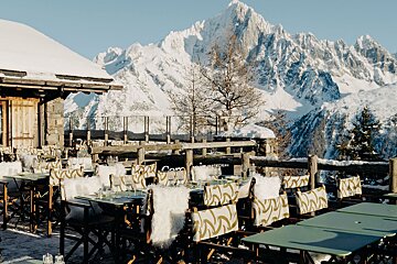 A row of tables and chairs in front of a snowy mountain