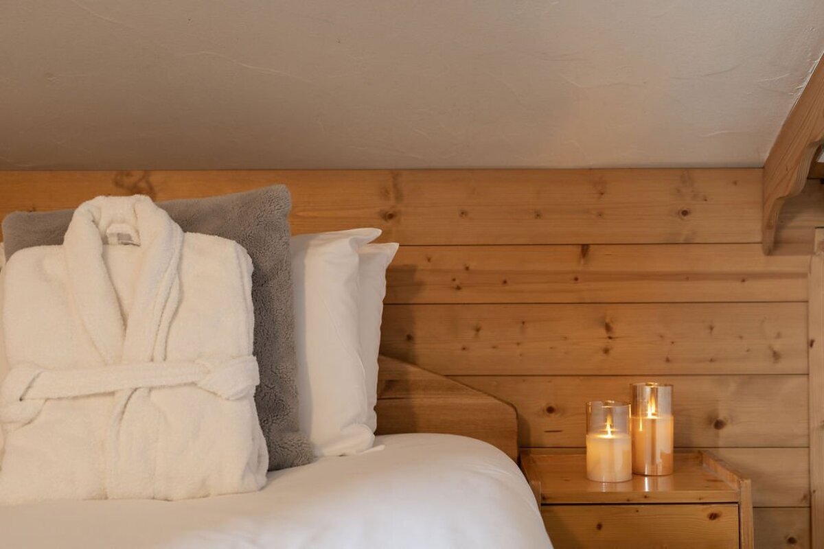 A bed with a robe and pillows and candles on the nightstand