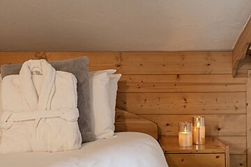 A bed with a robe and pillows and candles on the nightstand