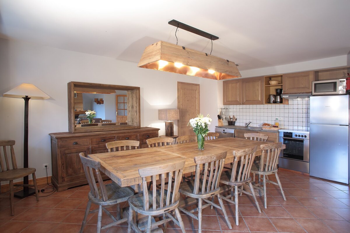 A kitchen with a table and chairs and a stainless steel refrigerator