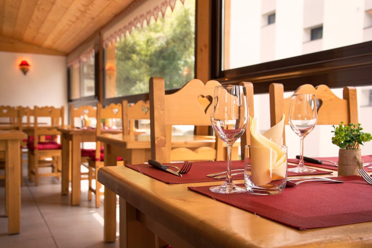 A restaurant with wooden tables and chairs and a glass of water on the table