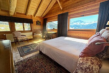 A bedroom with a large bed and a view of the mountains