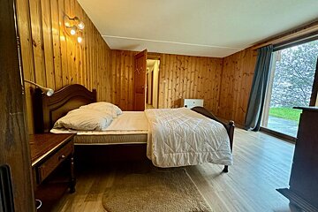 A bedroom with wood paneling and a large bed