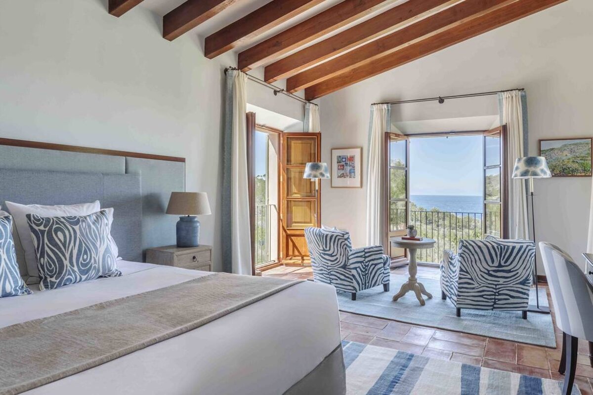 A bedroom with a large bed and a balcony overlooking the ocean