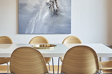 A dining room with a painting on the wall above the table