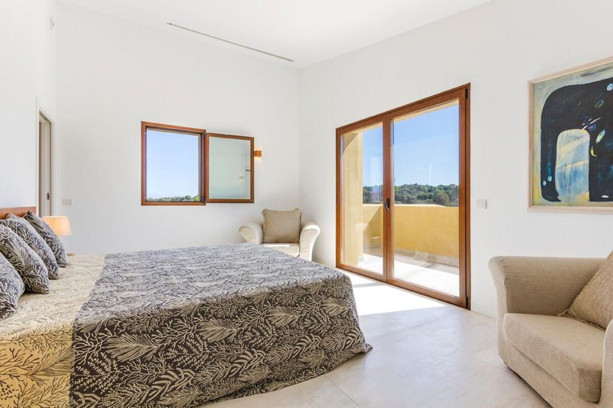 A bedroom with a bed a chair and a painting on the wall