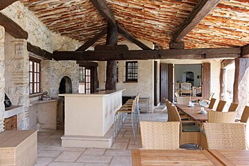 A dining room with wicker chairs and tables under a tiled roof