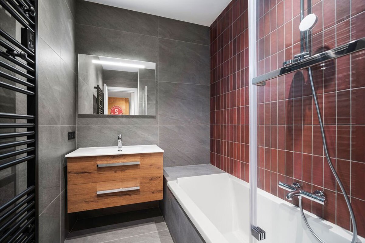 A bathroom with a sink and a bathtub with red tiles