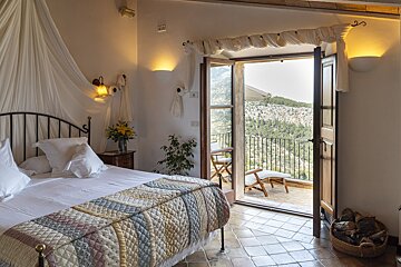 A bedroom with a canopy bed and a balcony