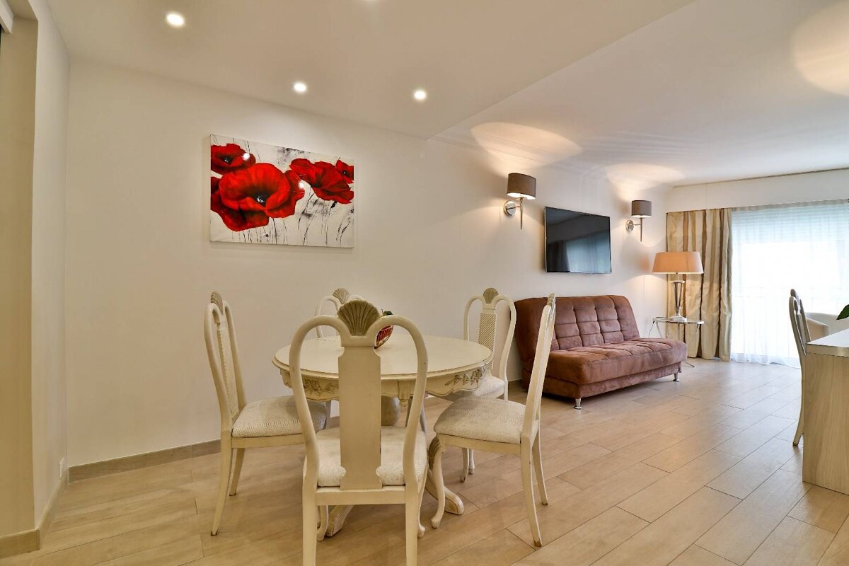 A living room with a table and chairs and a painting of red flowers on the wall