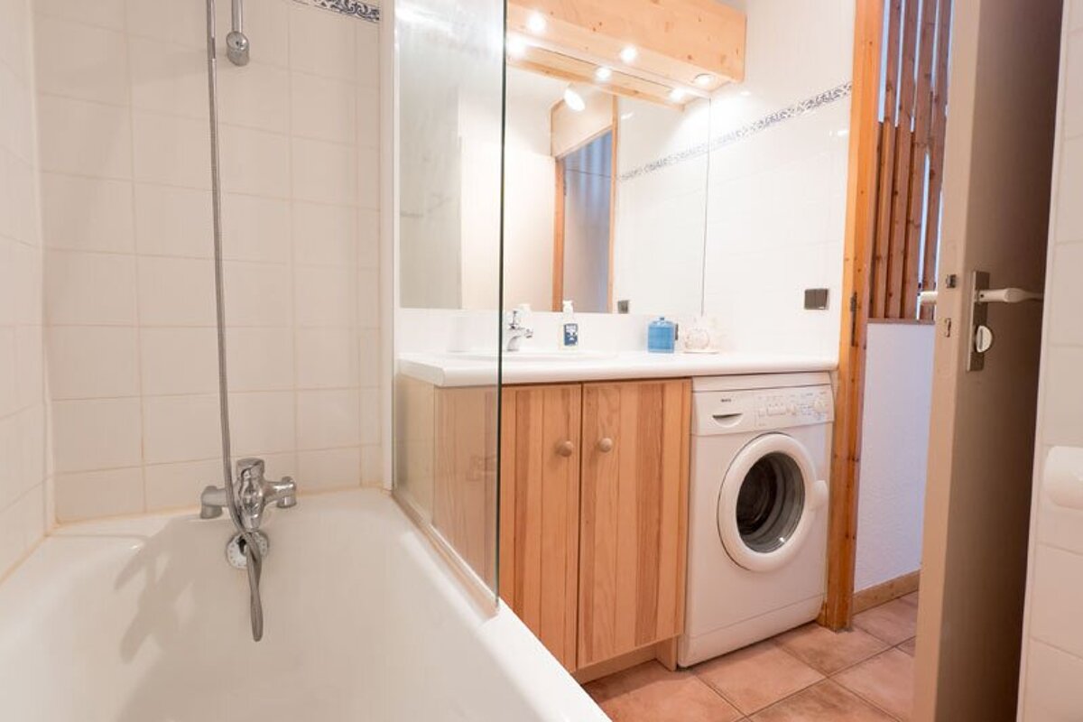 A bathroom with a washing machine and a bathtub