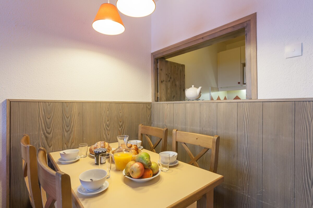 A table with a bowl of fruit and orange juice on it