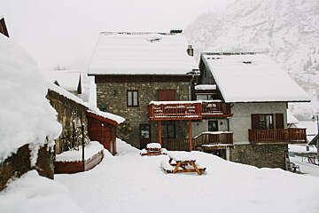 A snowy house with a picnic table in front of it