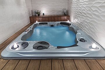 A hot tub with blue water and candles on the side