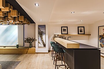 A bar in a living room with a painting of a mountain on the wall