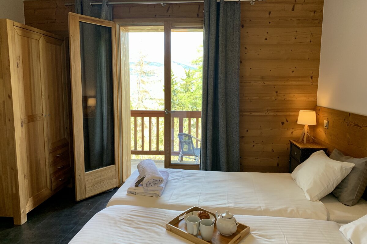 A bedroom with two beds and a balcony