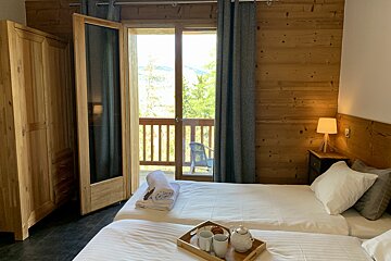 A bedroom with two beds and a balcony