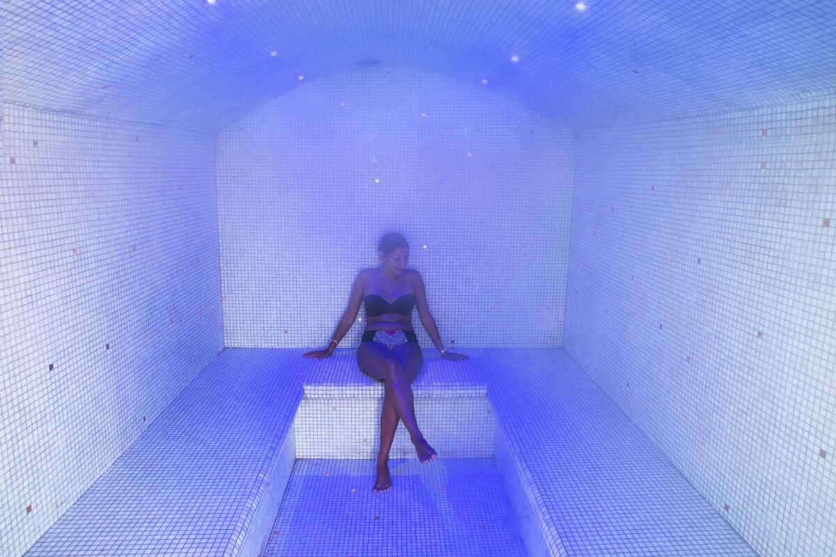 A woman in a bathing suit sits in a room with blue lights