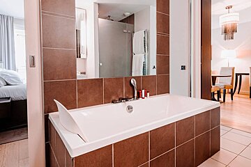 A bathroom with a bathtub and a mirror with the letter a on it