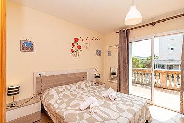 A bedroom with a sliding glass door that leads to a balcony