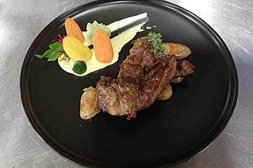 A black plate with meat and vegetables on it