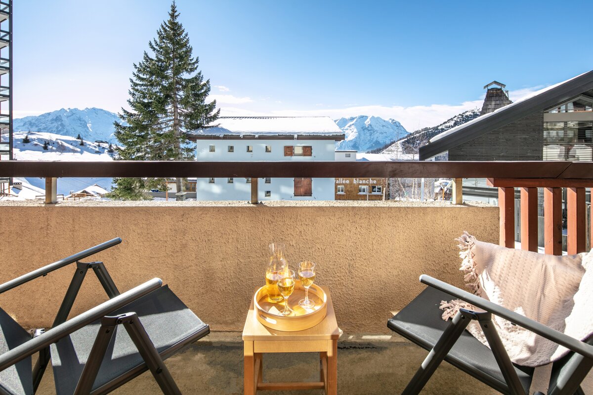 A balcony with two chairs and a tray of wine