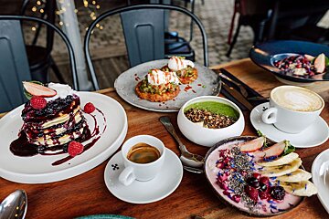 A table topped with plates of food including pancakes and smoothies