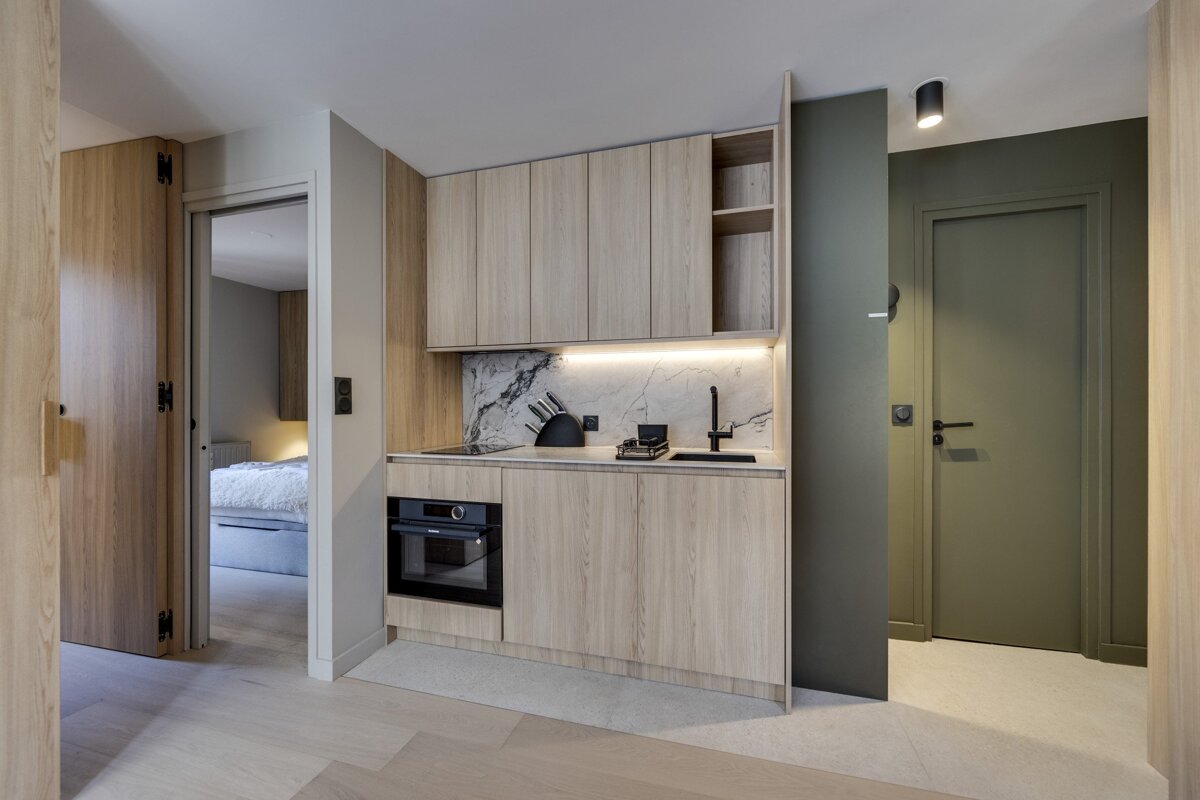 A kitchen with wooden cabinets and a marble counter top