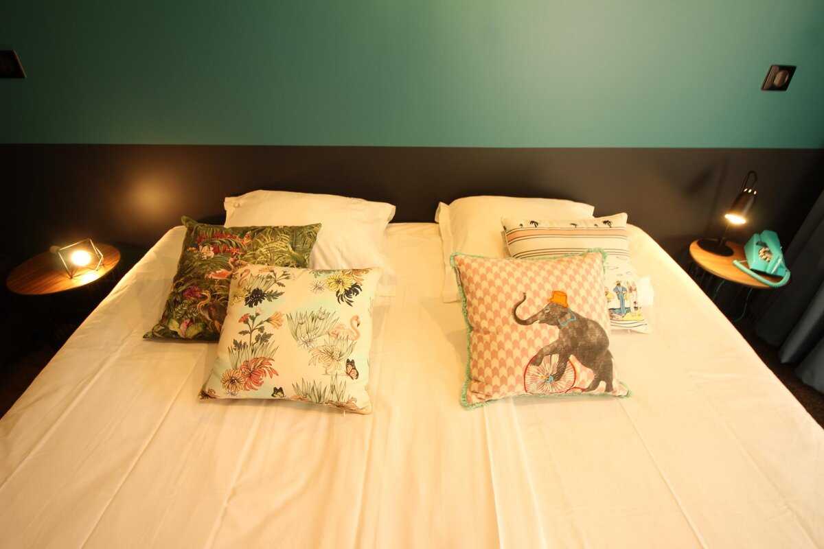 A bed with pillows on it including one with an elephant on it