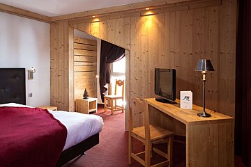 A hotel room with a bed a desk and a television