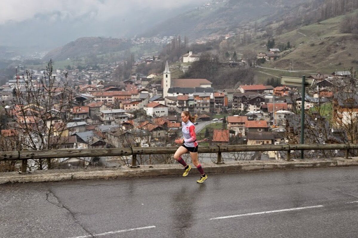 A woman is running down a road in front of a small town