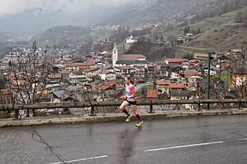 A woman is running down a road in front of a small town