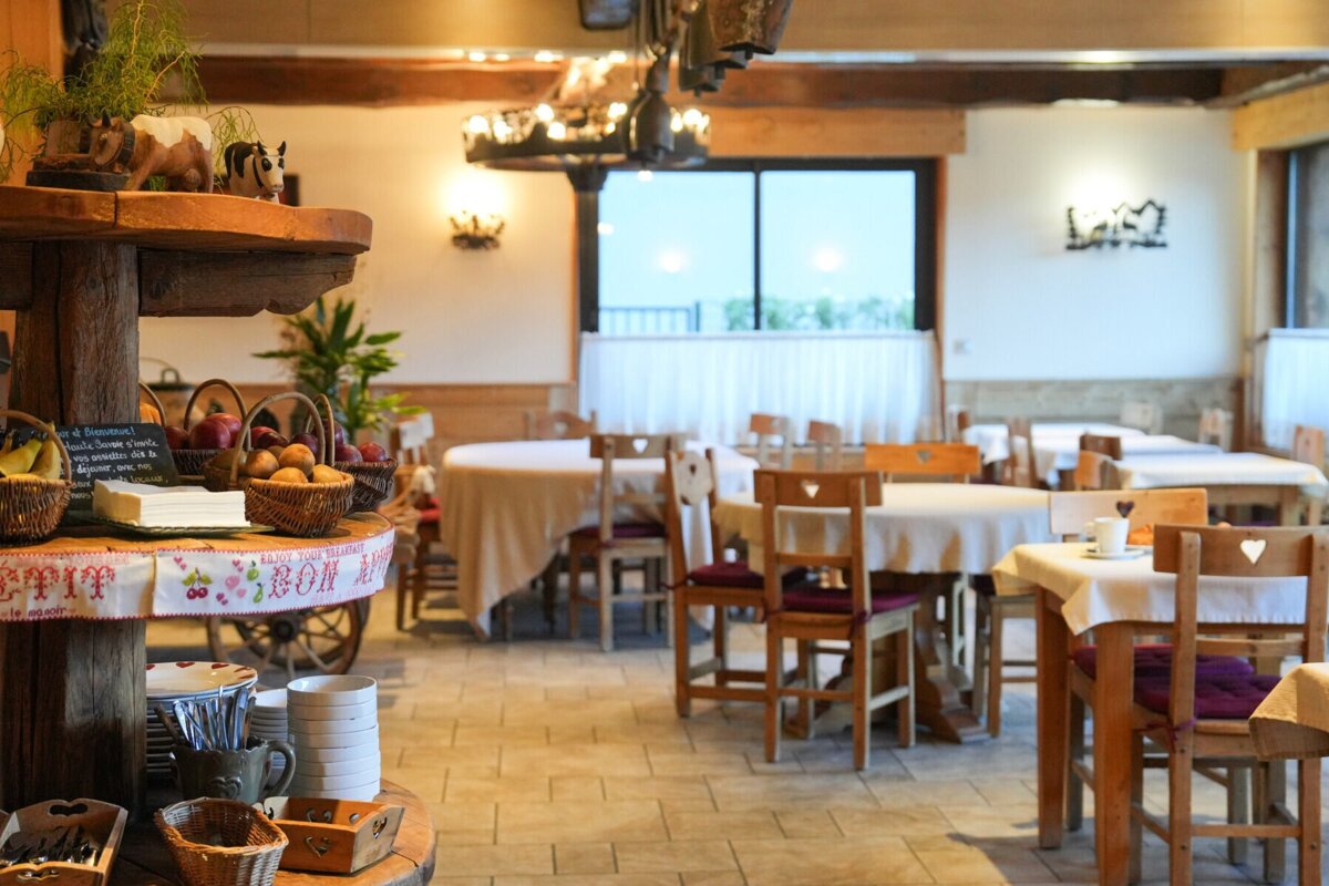 A dining room with tables and chairs and a basket of fruit on the table