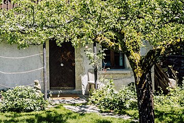 A house with a wooden door and a tree in front of it