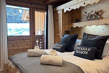 A bed with a pillow that says ' snuggle season ' on it