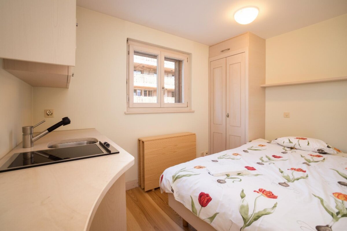 A small bedroom with a bed and a sink