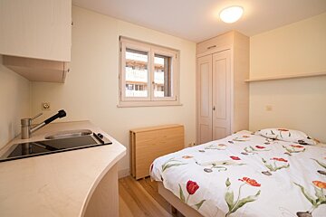 A small bedroom with a bed and a sink