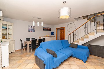 A living room with a blue couch and a clock on the wall