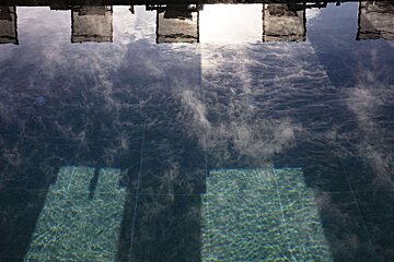 The sky is reflected in the water of a swimming pool