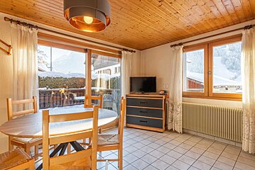 A living room with a table and chairs and a television