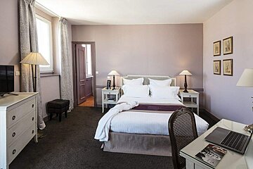 A hotel room with a bed and a desk with a laptop on it