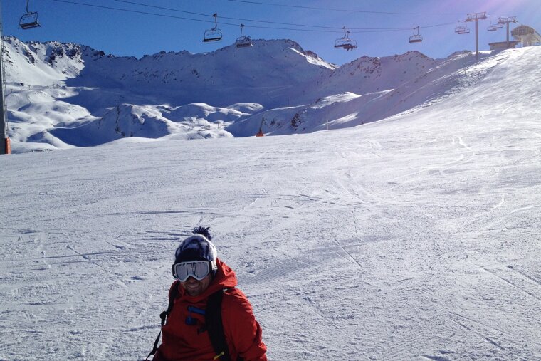 image of a snowboarder sat on the slopes in Val d'isere with a chairlift behind