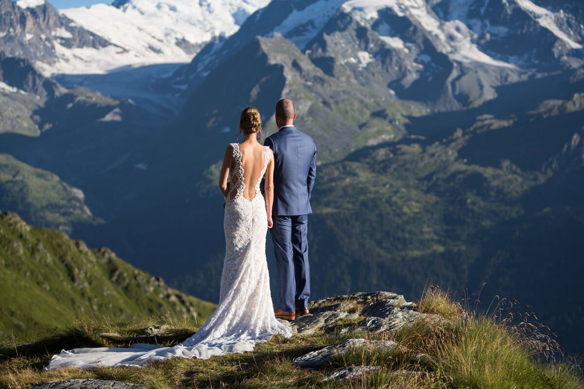 A bride and groom standing on top of a mountain