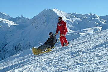 a ski instructor with a man on an adapted sledge