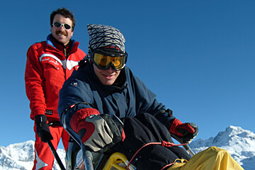 a ski instructor with a man on an adapted sledge