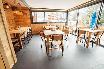 A restaurant with tables and chairs and a blue umbrella