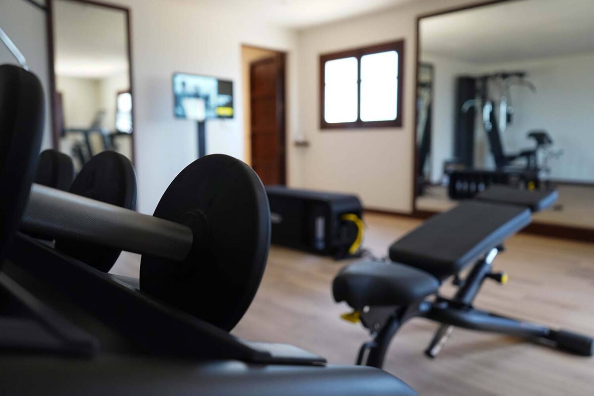 A gym with a bench and dumbbells in the foreground