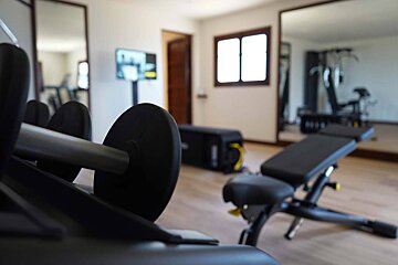 A gym with a bench and dumbbells in the foreground