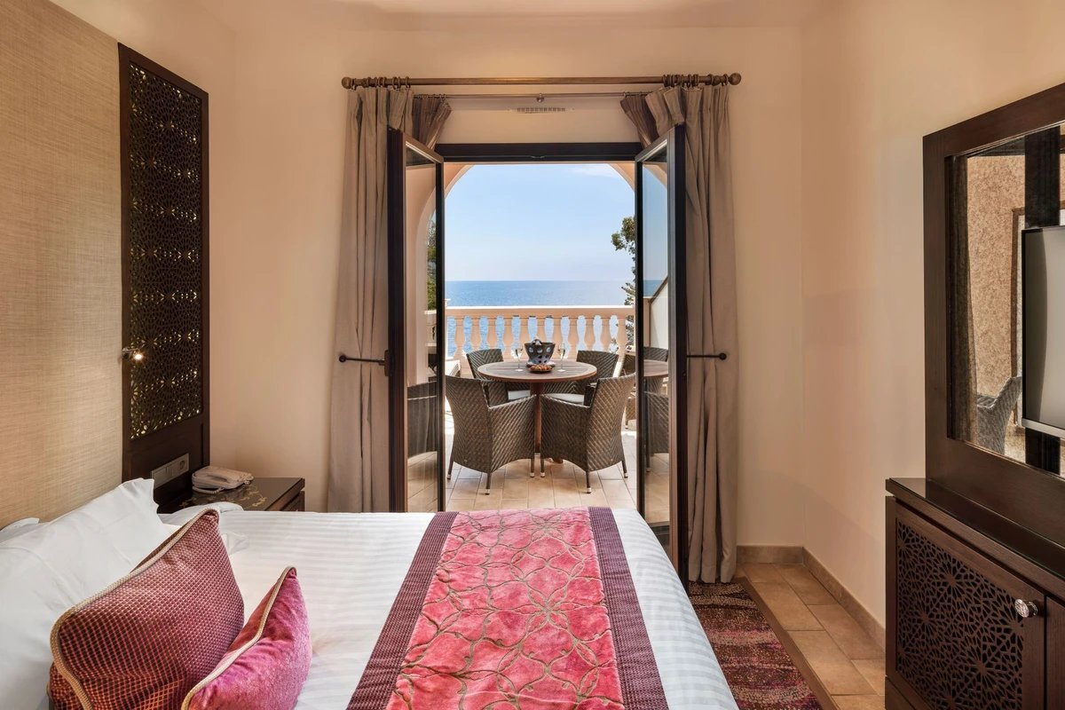 A hotel room with a balcony overlooking the ocean