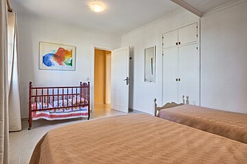 A bedroom with two beds and a red crib